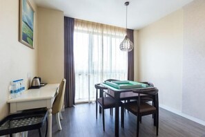 A hotel room with a dining table, chairs, a small kitchen area, and a window with curtains. - Fuda Fashion Hotel (Chongqing)