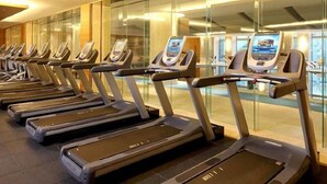 A row of treadmills in a well-lit indoor area with glass walls.