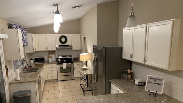 A modern kitchen with white cabinets, stainless steel appliances, and a granite countertop. - Bluedoor House Comfy Home close to NB, SA, & RAFB (Live Oak)
