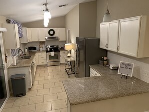 A modern kitchen with white cabinets, stainless steel appliances, and a granite countertop. - Bluedoor House Comfy Home close to NB, SA, & RAFB (Live Oak)