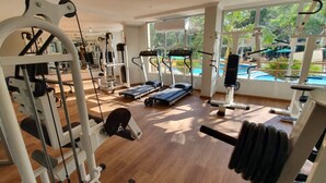 Un gimnasio con máquinas de cardio, equipo de levantamiento de pesas y una cinta de correr.