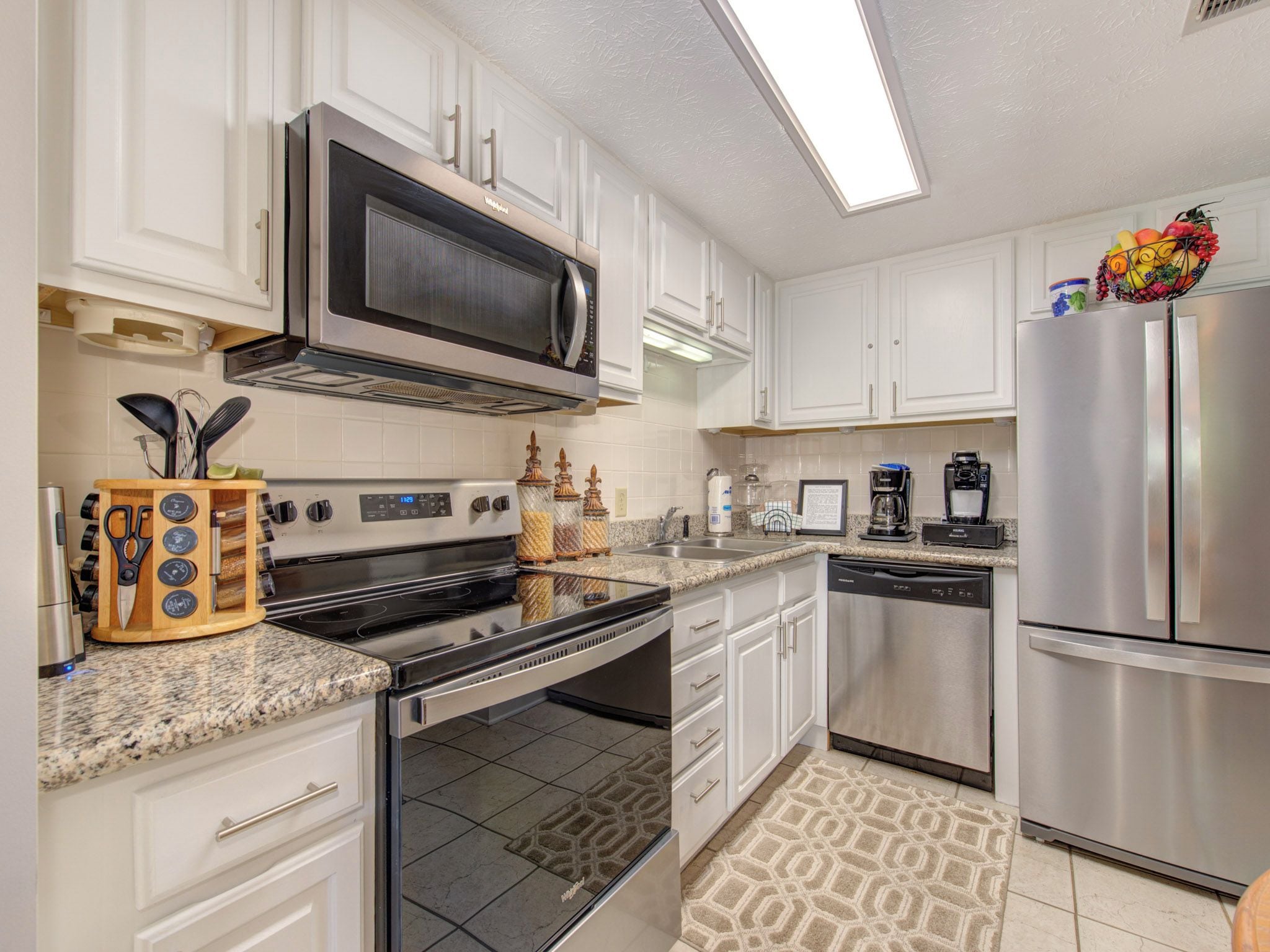 A modern kitchen with white cabinets, stainless steel appliances, and a granite countertop.