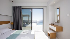 Une chambre d’hôtel moderne dotée d’un lit, d’une salle de bain, d’un balcon avec vue sur la mer et d’une grande fenêtre.
