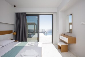 A modern hotel room with a bed, a bathroom with a vanity, and a balcony with a view of the sea.