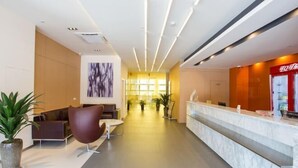 Eine moderne Hotellobby mit einer Rezeption, einer Sitzecke und einem großen abstrakten Gemälde an der Wand.