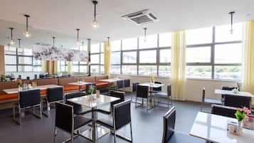A modern dining area with tables and chairs, large windows, and a view of the city.