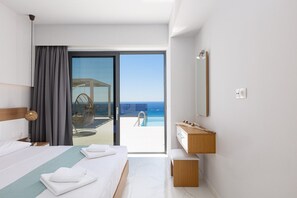 A hotel room with a bed, a bedside table, a mirror, a wooden dresser, and a sliding glass door leading to a balcony with a pool and ocean view. - New villa in Falasarna bay★Seaview★Infinity pool (Phalasarna)