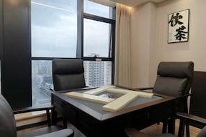 A modern conference room with a large table, two chairs, and a view of a cityscape through a large window. - Hexi Hotel (Tongliang Wanda Plaza Branch) (Chongqing)