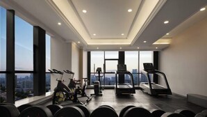 Ein modernes Fitnessstudio mit Laufbändern, Kraftgeräten und einem großen Fenster mit Blick auf die Stadt.