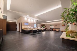 A spacious hotel lobby with a reception desk, seating area, and a large plant. - Hexi Hotel (Tongliang Wanda Plaza Branch) (Chongqing)
