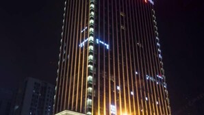 Ein hohes, beleuchtetes Gebäude mit vertikalen Linien und einem zentralen Lichtelement.