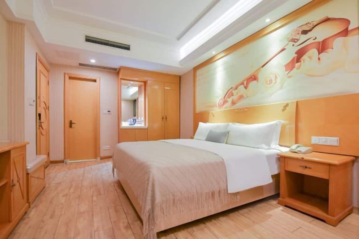 A hotel room with a bed, bedside table, and a large mirror.