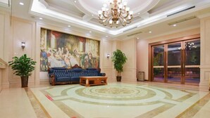 Eine Lobby mit einem großen Wandgemälde, einem blauen Sofa, einem Holztisch und einem gemusterten Boden.