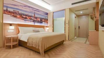 A hotel room with a bed, bedside table, and a large cityscape painting on the wall.