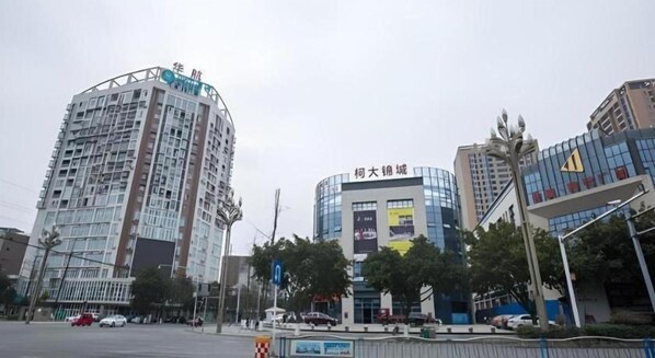 A multi-story building with a curved facade, large windows, and signage indicating a commercial area. - City Comfort Inn Deyang Shifang Yonghu Park (Deyang)