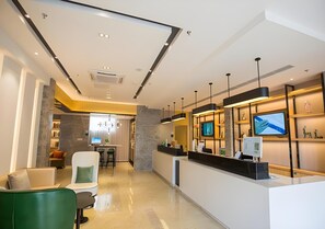 A modern reception area with a counter, seating, and a TV screen. - City Comfort Inn Deyang Shifang Yonghu Park (Deyang)