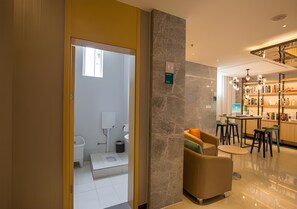 A modern hotel room with a bathroom, a seating area with a table, and a bar area with bookshelves. - City Comfort Inn Deyang Shifang Yonghu Park (Deyang)