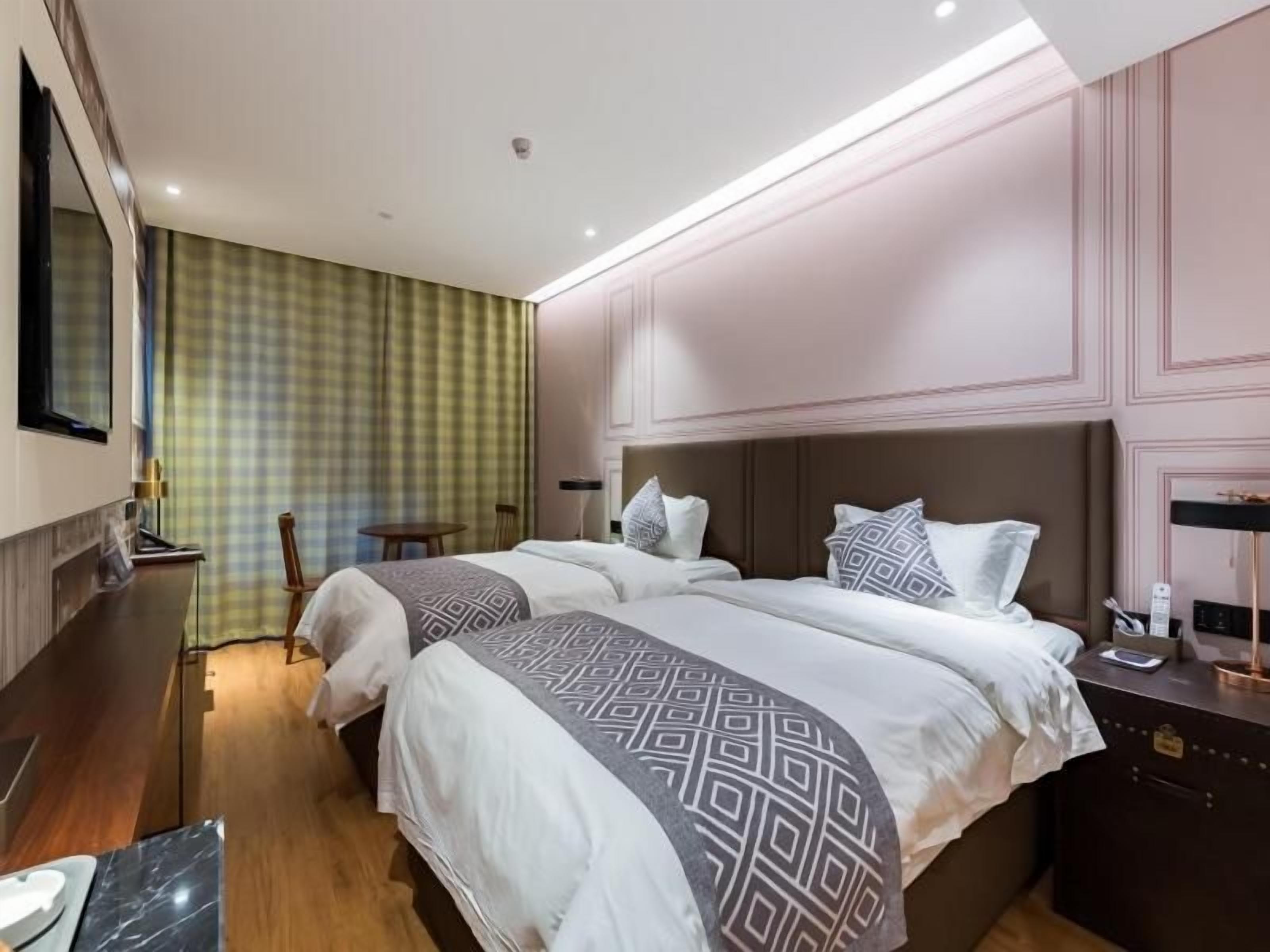 A hotel room with two beds, a desk, and a chair.