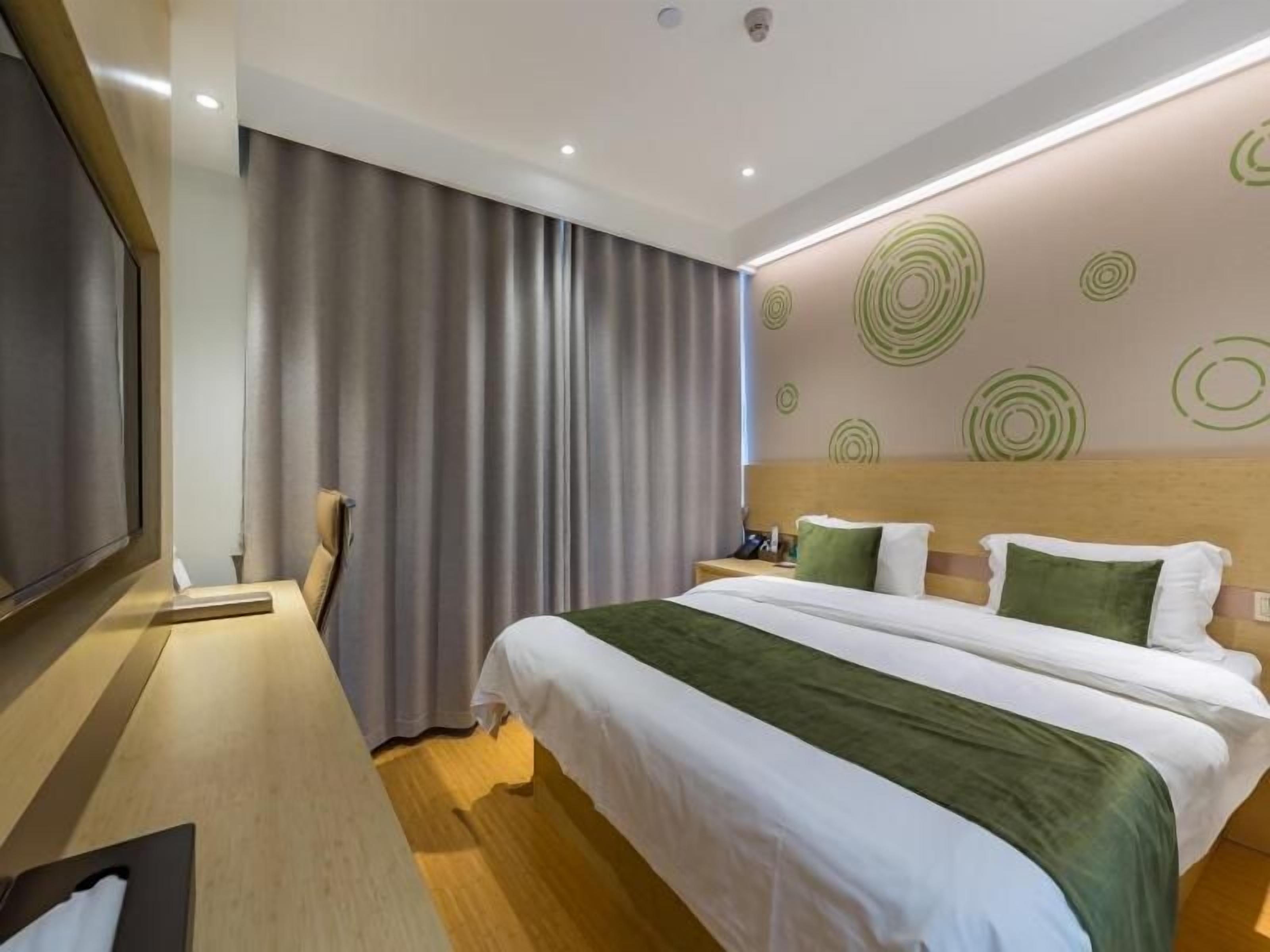 A hotel room with a large bed, a flat-screen TV, and a curtain.