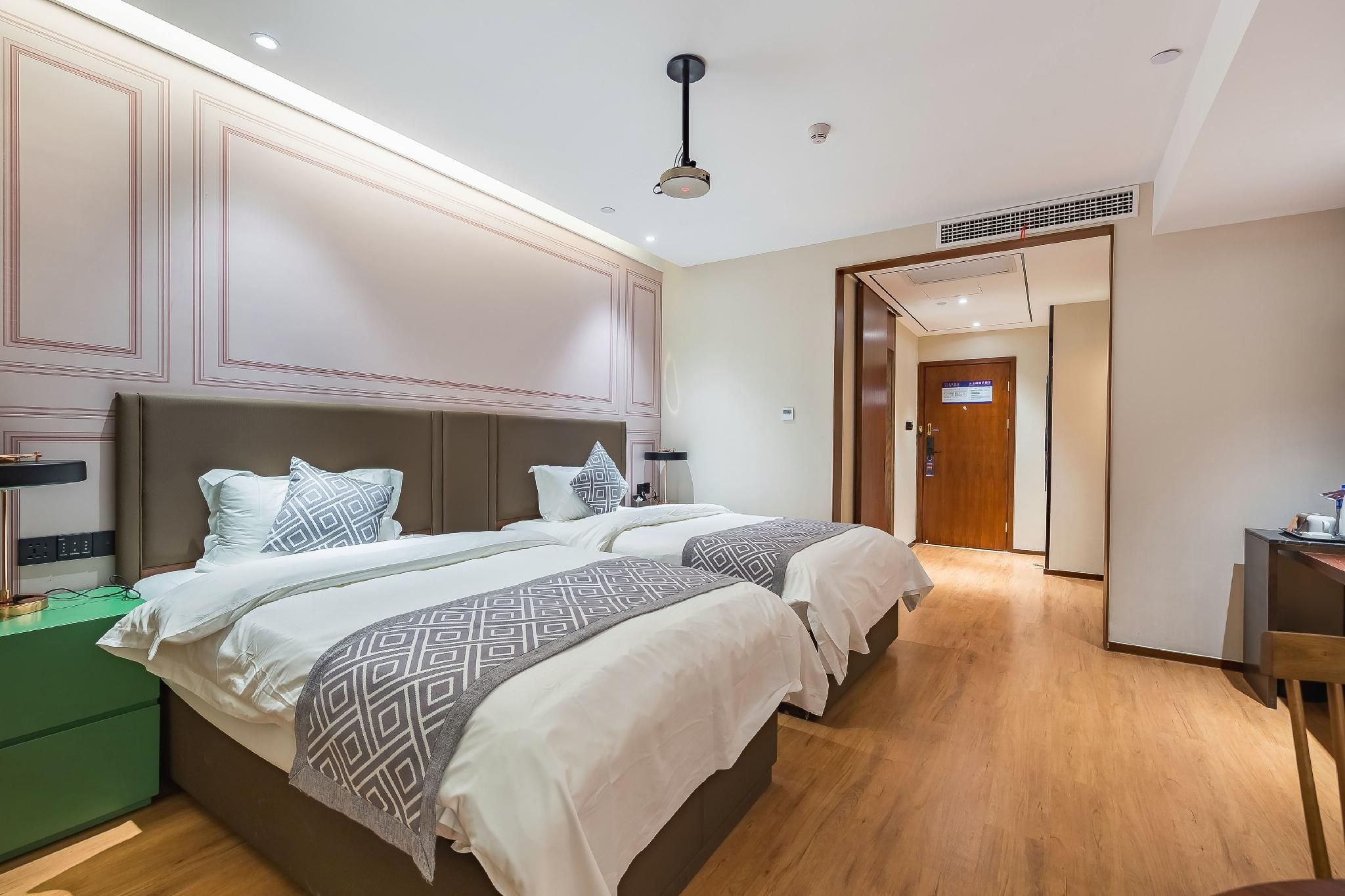 A hotel room with a large bed, bedside tables, a desk, and a wardrobe.