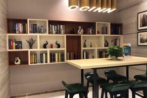 A library with bookshelves, a table, and chairs. - City Comfort Inn (Zhongshan Dongfeng Town Government) (Zhongshan)