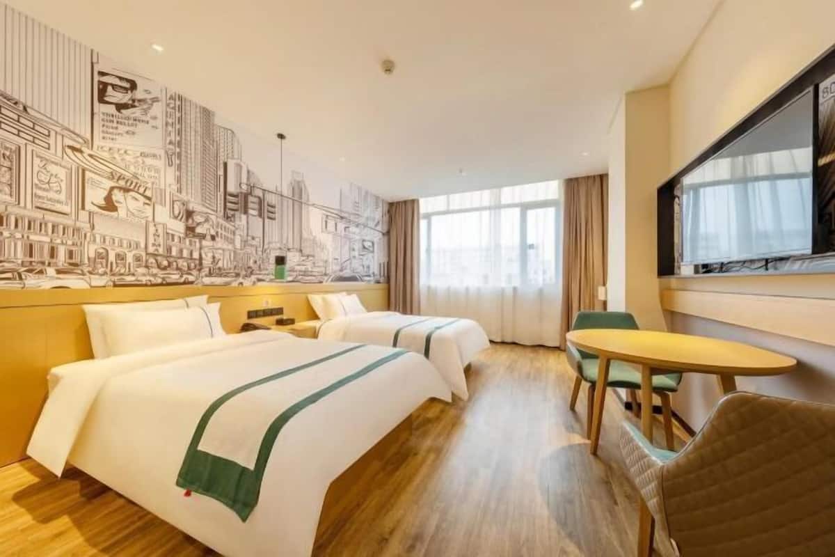 Ein Hotelzimmer mit zwei Betten, einem Esstisch und einem großen Fenster.