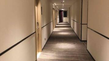 Un pasillo de hotel con pisos alfombrados, puertas a ambos lados y una larga extensión.