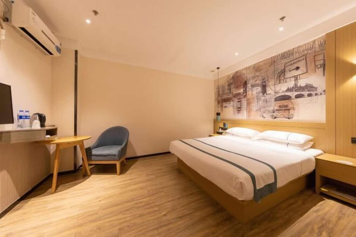 Ein Hotelzimmer mit Bett, Schreibtisch, Stuhl und einer Wand mit Stadtbild-Mural.