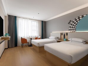 Hotellihuone, jossa on kaksi sänkyä, työpöytä, tuoli, pieni pöytä ja ikkuna, jossa on verhot.