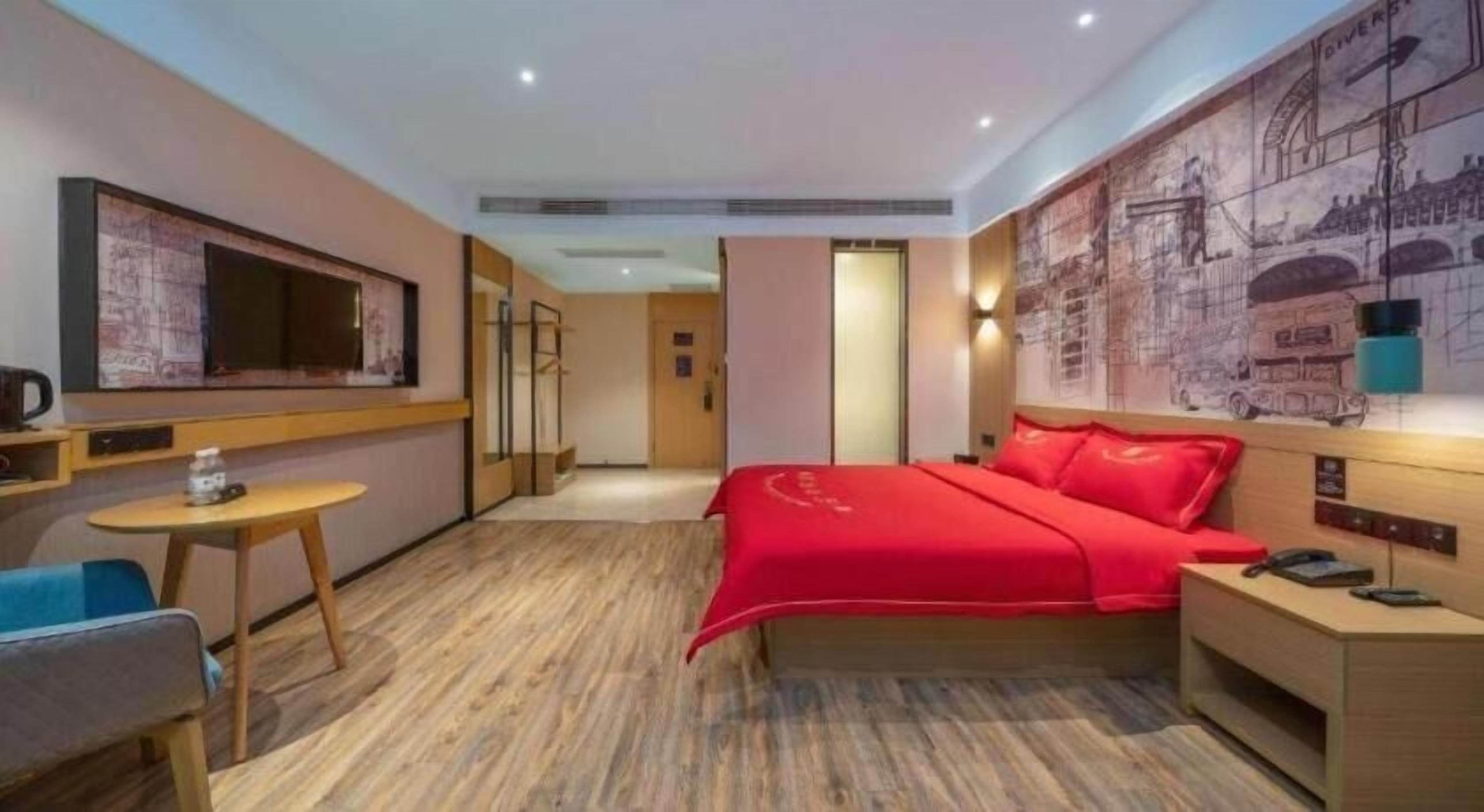 A hotel room with a bed, a desk, a chair, a television, and a wall with a mural.