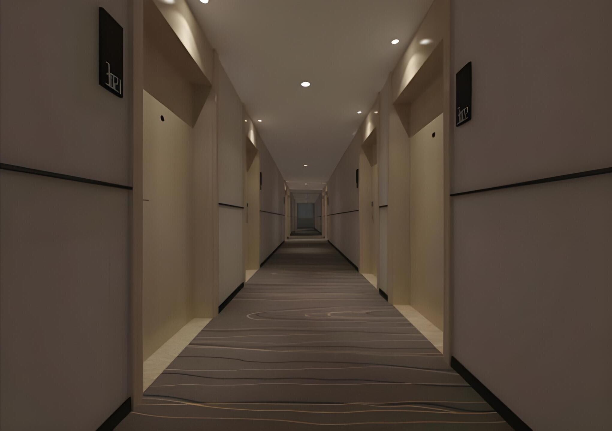 Un largo y estrecho pasillo de hotel con piso alfombrado, iluminación empotrada y puertas a ambos lados.