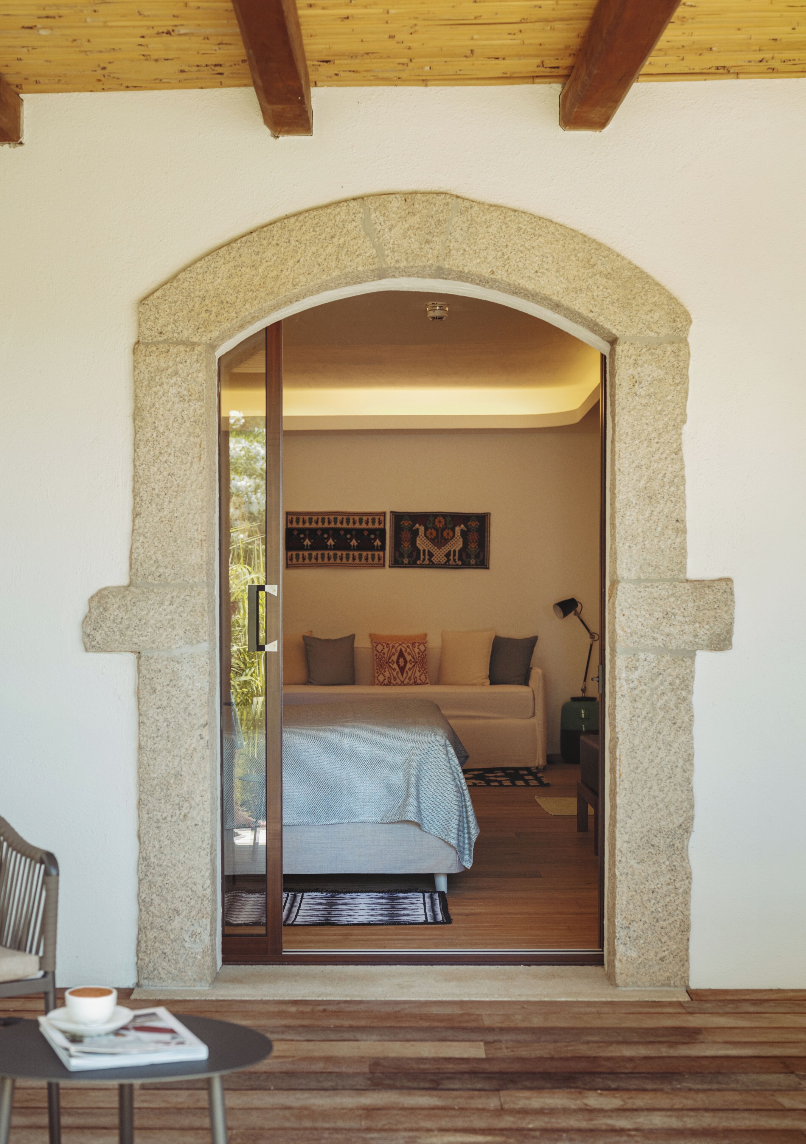 Un dormitorio con cama, sofá, una mesita de centro y una puerta que da a un balcón.