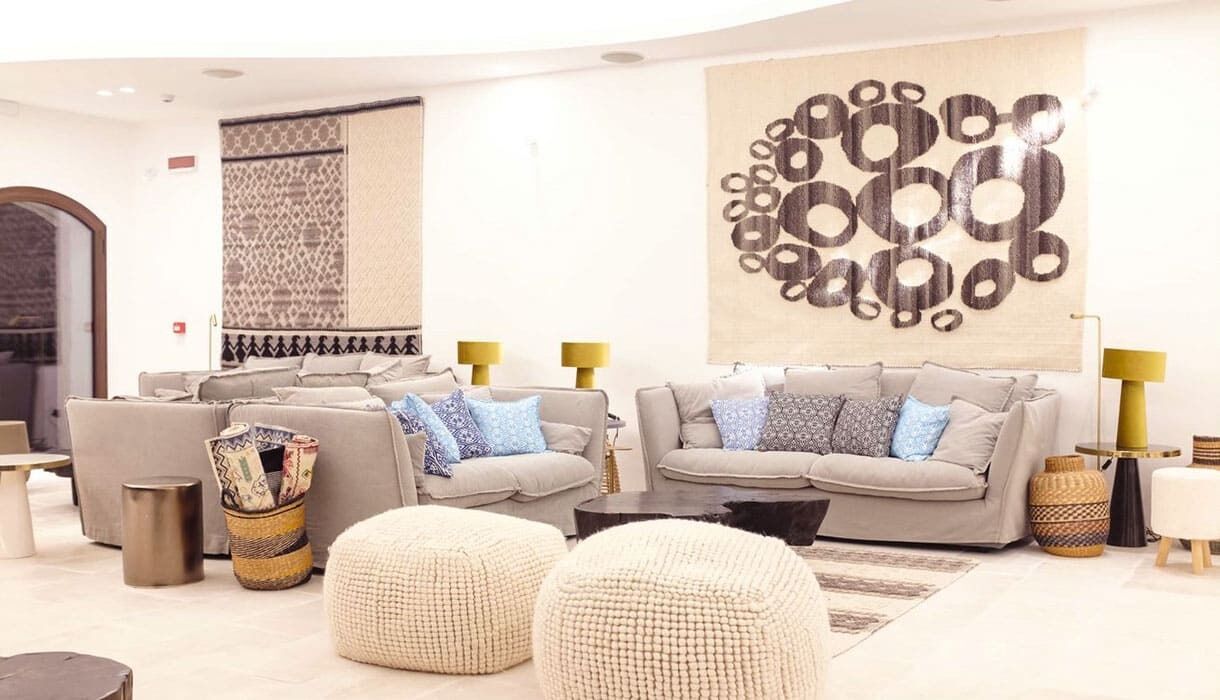 Una sala de estar moderna con dos sofás, una mesa de centro y almohadones decorativos. Hay dos lámparas y una gran obra de arte abstracta en la pared.