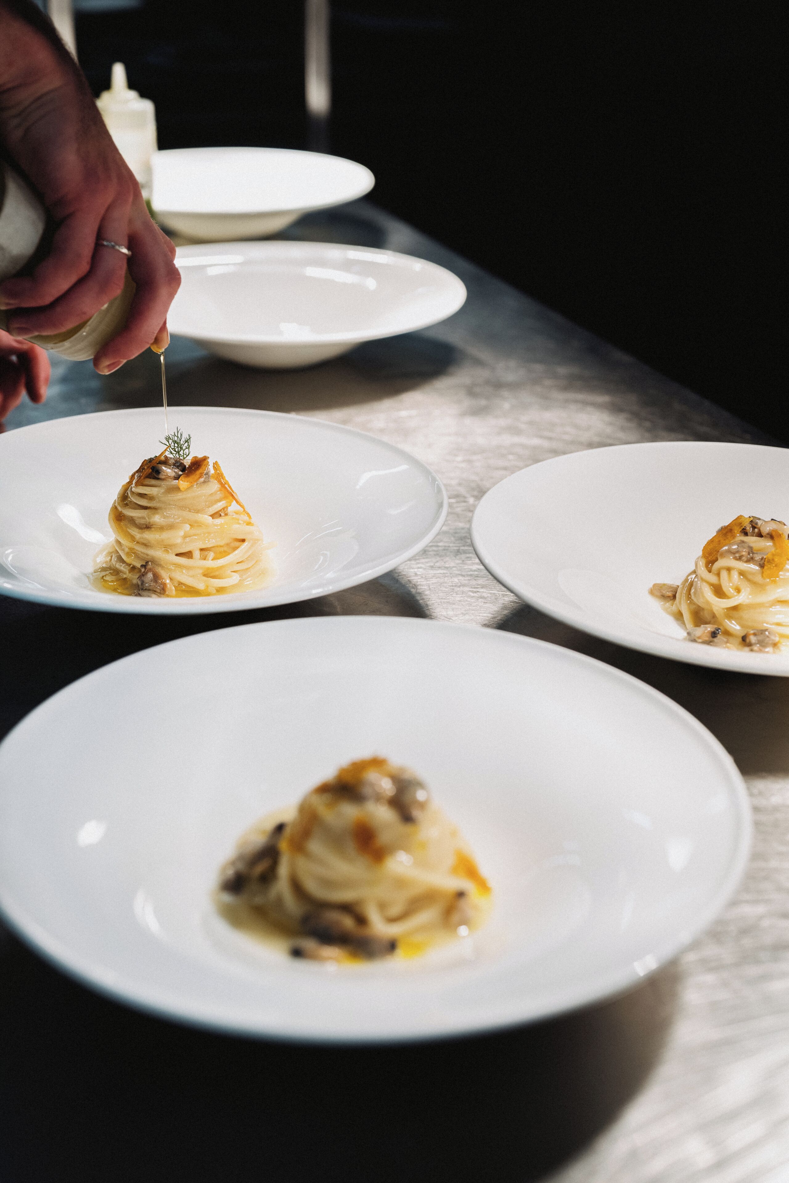 Three white plates with pasta dishes on a table.