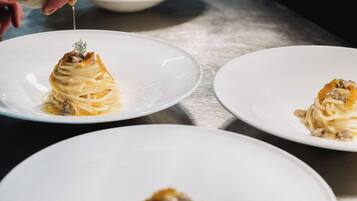Three white plates with pasta dishes on a table.