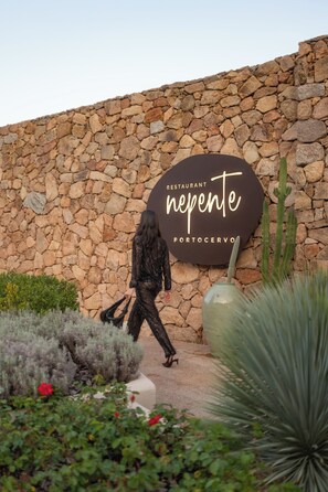 A stone wall with a sign for 'nepente portocervo' restaurant. - Hotel Delle Rose a Luxury Boutique Hotel (Arzachena)