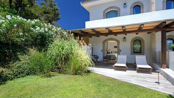 Una casa moderna con porche cubierto, mobiliario de exterior y un jardín exuberante.