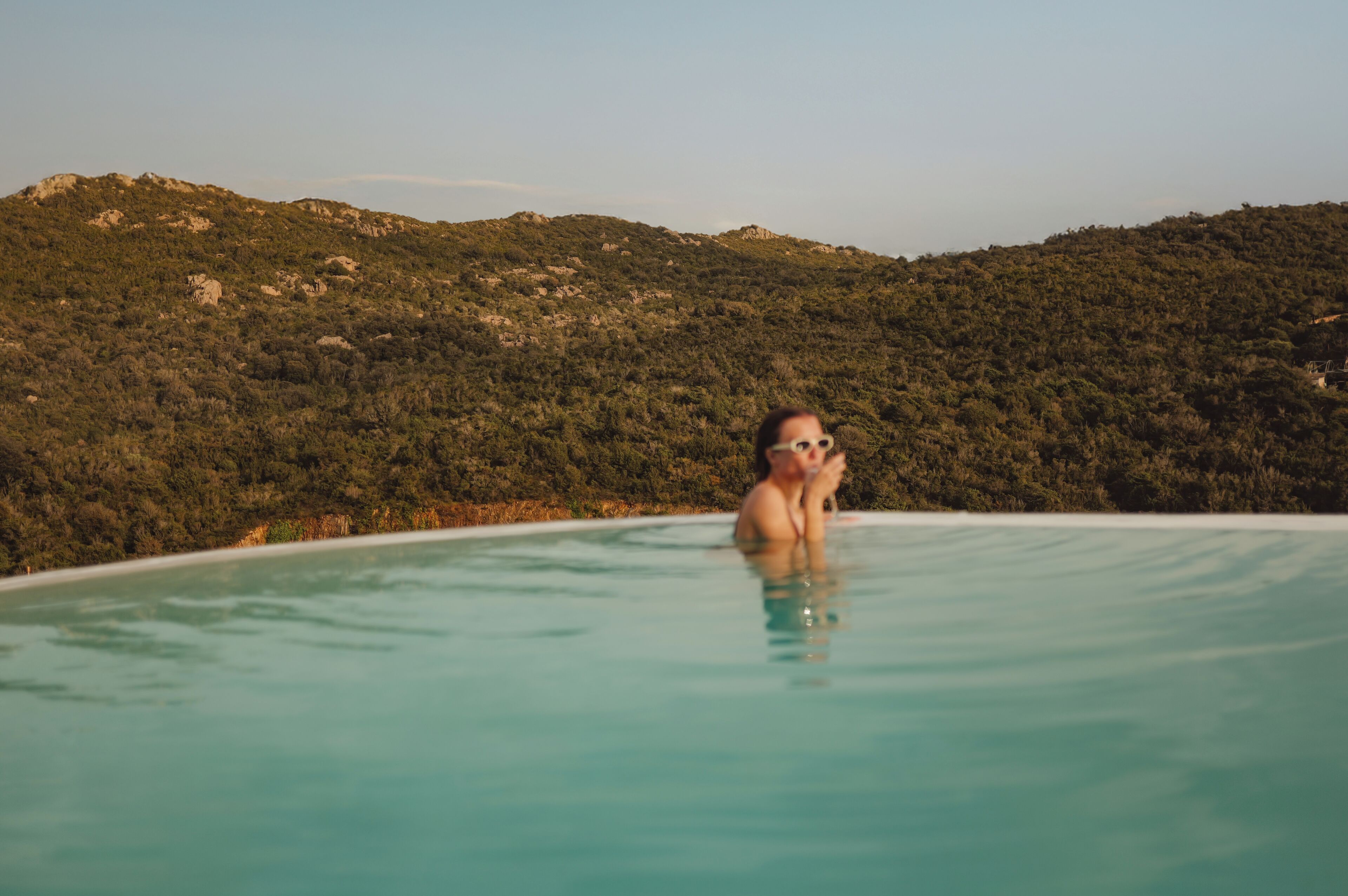 A person in a swimming pool with a mountainous landscape in the background.
