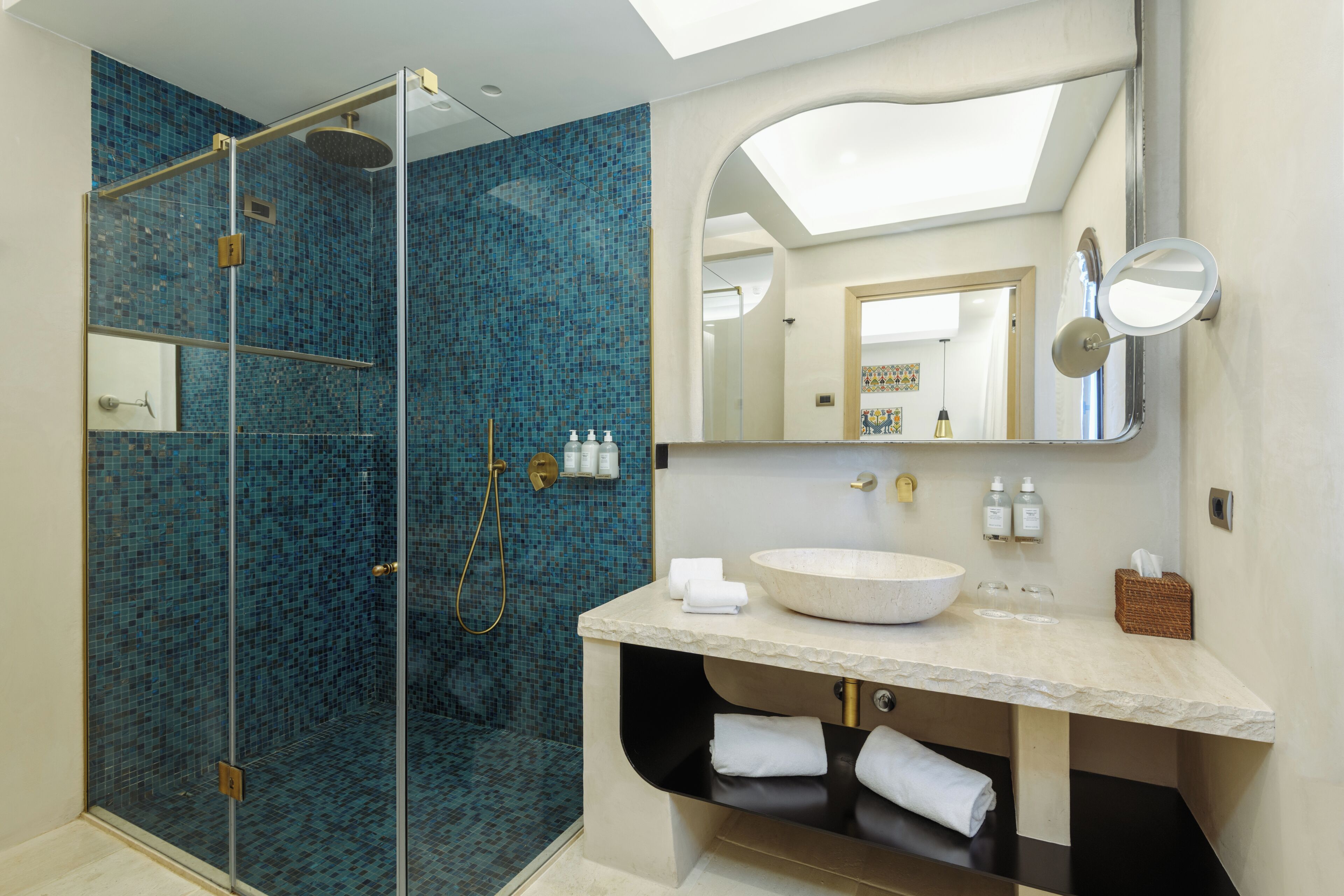 A modern bathroom with a glass-enclosed shower, a large mirror, and a vanity with a bowl sink.