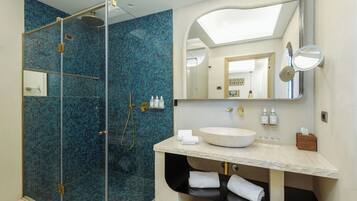 A modern bathroom with a glass-enclosed shower, a large mirror, and a vanity with a bowl sink.
