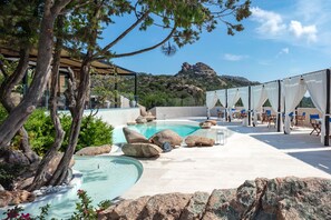 A pool area with natural rock formations, seating, and a view of a mountainous landscape. - Hotel Delle Rose a Luxury Boutique Hotel (Arzachena)