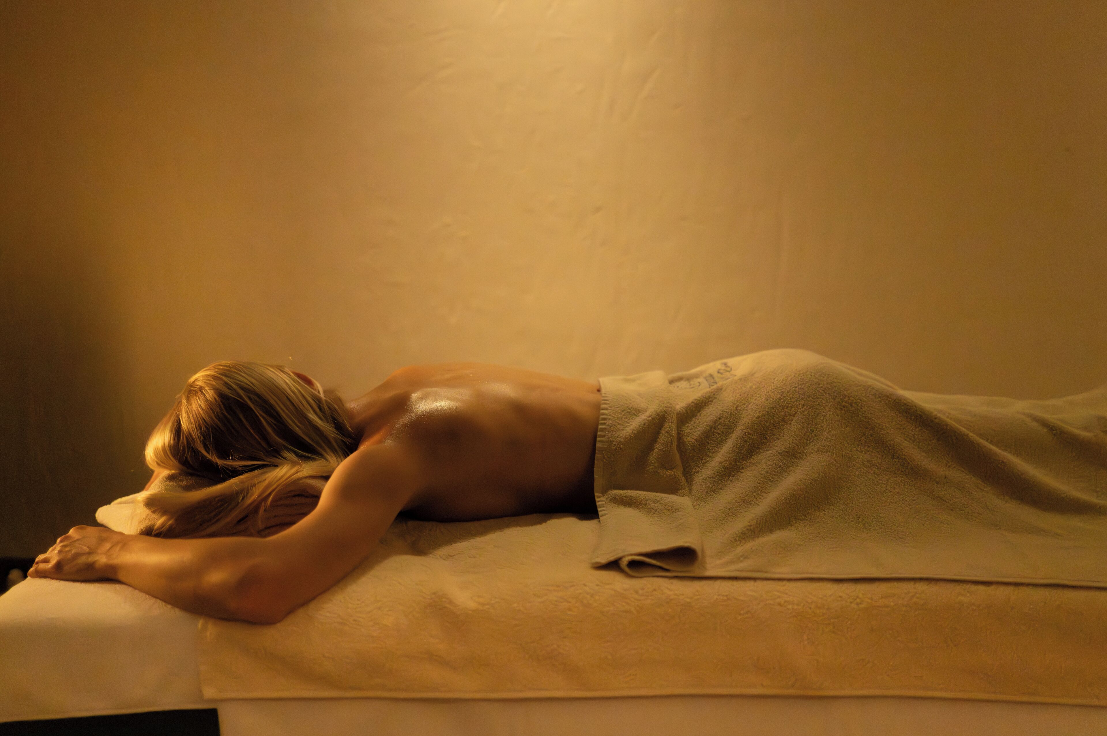 Una persona acostada en una cama con una almohada blanca y una manta.