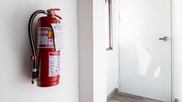 A red fire extinguisher mounted on a wall next to a door with a metal handle.