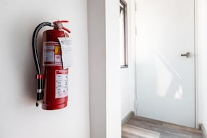 Un extincteur rouge est fixé au mur, à côté d’une porte dotée d’une poignée en métal.