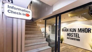 Una escalera que lleva a un hostal, con un cartel de recepción de información.