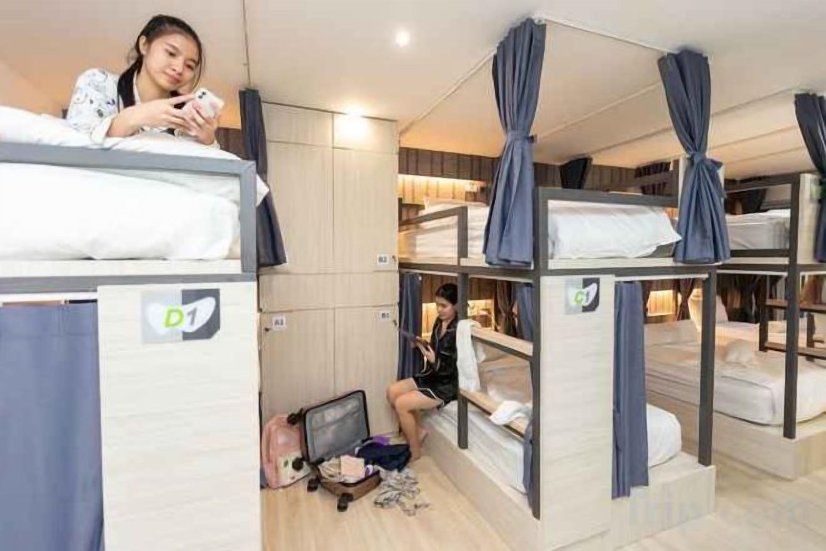A dormitory-style room with bunk beds, a desk, and a chair.