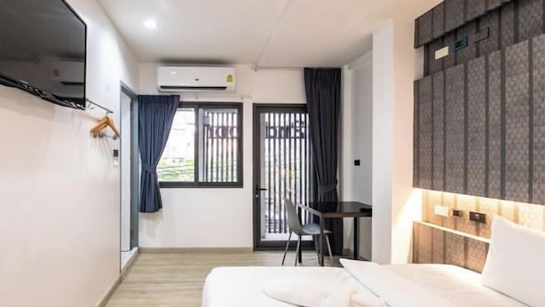Una habitación de hotel moderna con cama, escritorio, silla y vistas por una ventana.