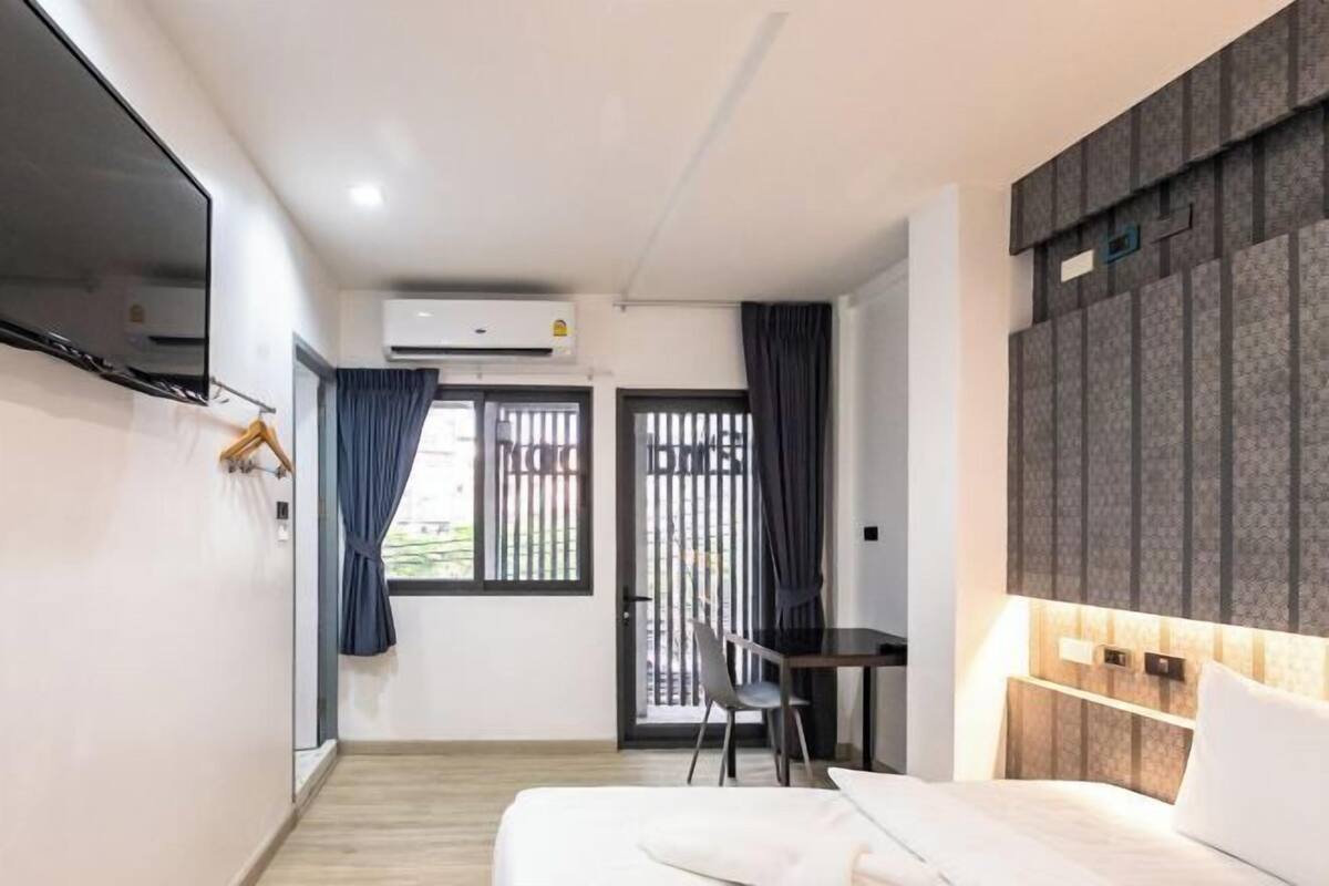 Een moderne hotelkamer met een bed, bureau, stoel en uitzicht door een raam.