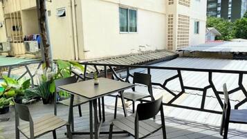 An outdoor seating area with a table and chairs, surrounded by potted plants.