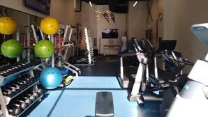 Ein Fitnessstudio mit Trainingsgeräten, darunter Laufbänder, Kraftgeräte und Medizinbälle.